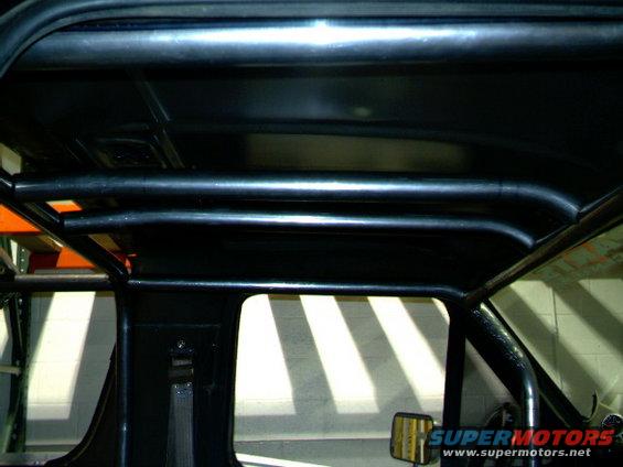 Interior roll cage with black tubing and a partial view of a side mirror