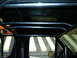 1989 Ford Bronco - The interior of a vehicle shows a custom black roll cage structure overhead and along the sides.