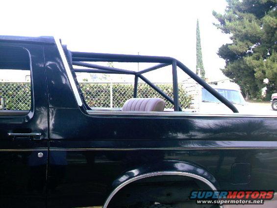 Black Ford Bronco side view with aftermarket roll cage and tan seat