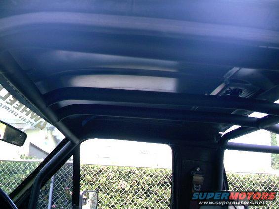 Interior view of a roll cage with a partial view of a side mirror and text on a sticker