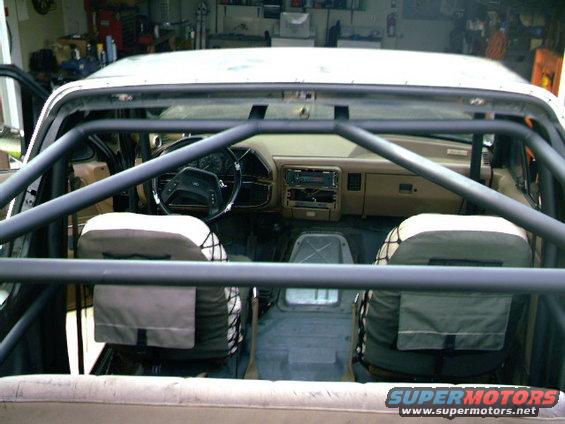 Interior of a 1989 Ford Bronco with a prominent roll cage and tan seats