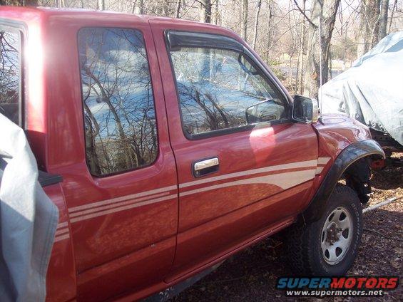 Side view of a red pickup truck with white stripes on the door