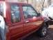1995 Toyota Tacoma - The side of a red pickup truck is shown, with trees reflected in the windows.