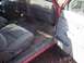 1995 Toyota Tacoma - The interior of a red truck shows a dirty floor and worn grey seats, with the driver's side door ajar.