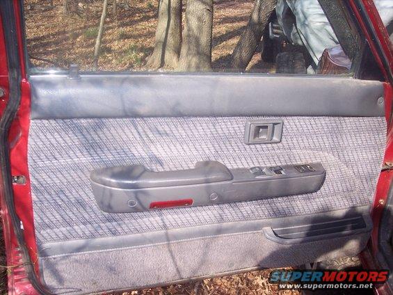 Interior of a car door showing the armrest, window controls, and door handle