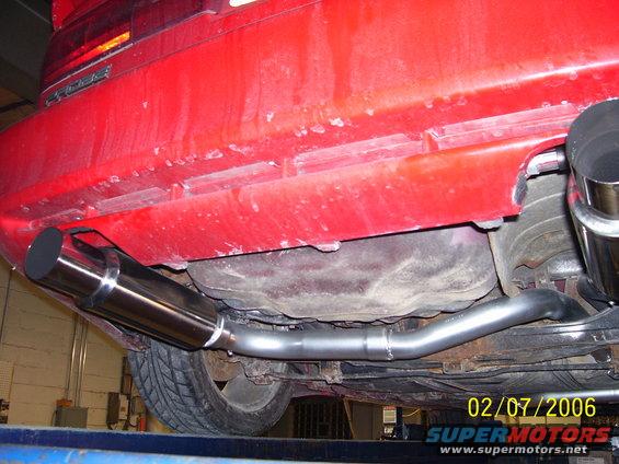 Underside of red car showing custom exhaust pipes and muffler