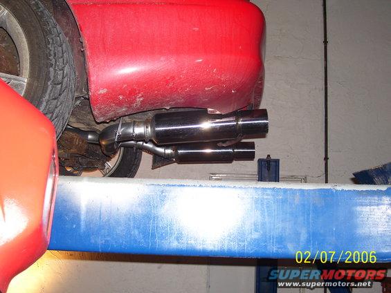Red car's dual exhaust pipes visible from underneath