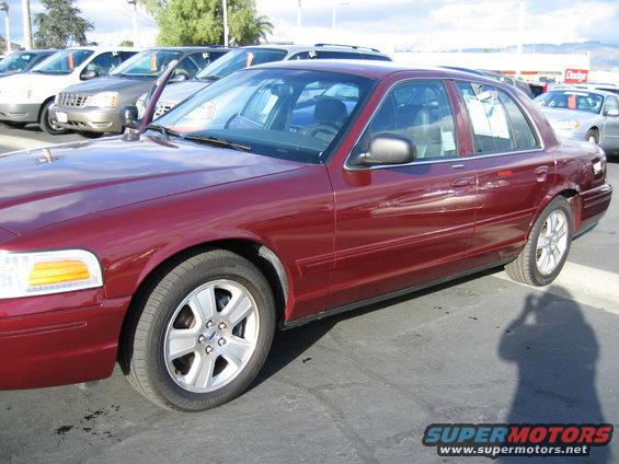 Red 2005 Ford Crown Victoria parked in a lot with other cars behind it