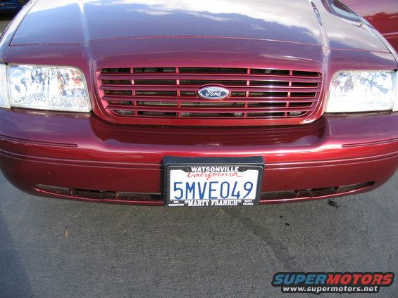 Front of a red Ford Crown Victoria with a Ford badge on the grille and a California license plate