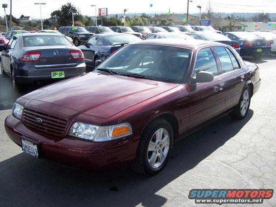 Maroon sedan parked at a car lot, other cars in background