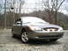 2001 Ford Taurus - A gray sedan is parked on a gravel lot with trees in the background.