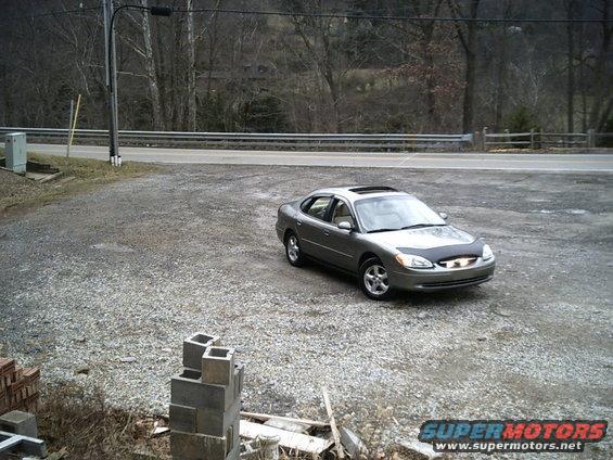 Silver 2001 Ford Taurus sedan with sunroof parked in a gravel lot