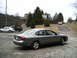 2001 Ford Taurus - A 2001 Ford Taurus is parked on a gravel lot, with other vehicles and a house in the background.