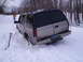 2000 Chevrolet Tahoe - A silver Chevrolet Tahoe is stuck in deep snow on a wooded path, with a person standing nearby.