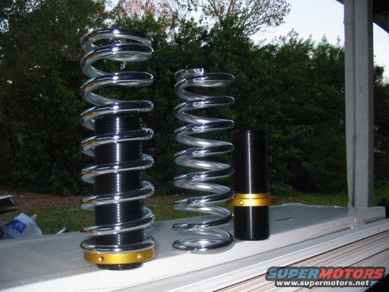 Coilover suspension parts with chrome springs and black bodies with gold accents