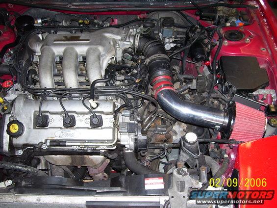 Red 1994 Ford Probe engine bay with a Ford V6 engine, aftermarket intake, and visible date stamp