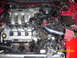 1994 Ford Probe - The engine bay of a red 1994 Ford Probe shows a V6 engine with an aftermarket cold air intake system.