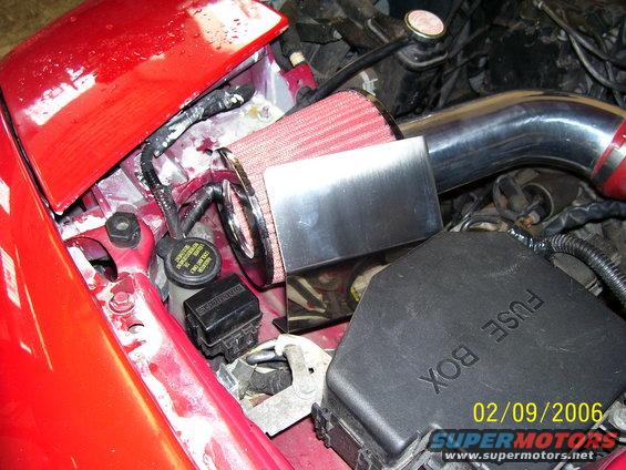 engine bay with red hood, aftermarket air filter, and fuse box