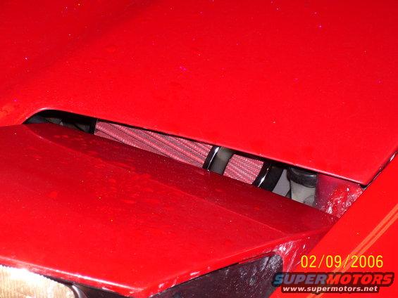Red car engine bay with an exposed red aftermarket air filter visible under the hood