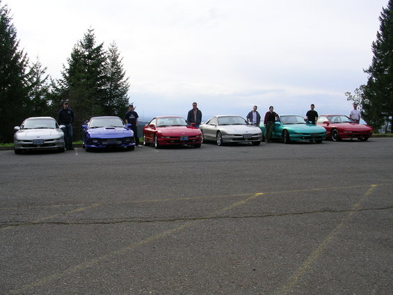 Several Ford Probe cars parked in a lot with people standing by them