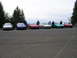 1996 Ford Probe - A group of Ford Probe cars are gathered together in a parking lot with several people standing around them.