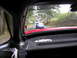 1996 Ford Probe - A blue sports car is seen driving on a road surrounded by trees, viewed through the rear window of another car.