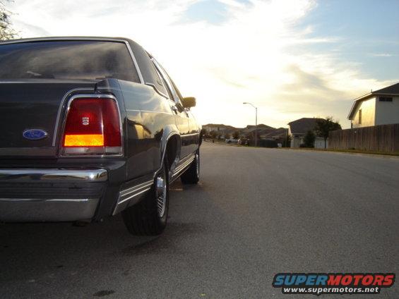 Rear quarter view of a dark sedan parked on a suburban street during sunset