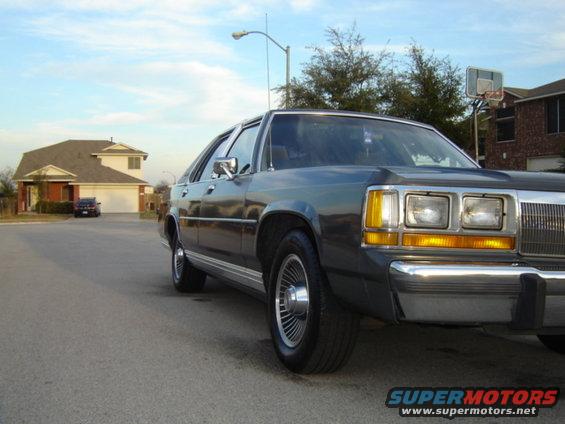 Dark sedan, 1988 Ford Crown Victoria, parked on a suburban street, front 3/4 view