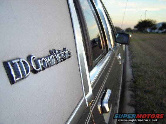 Close-up of LTD Crown Victoria badge on a light-colored car door, chrome trim, side view