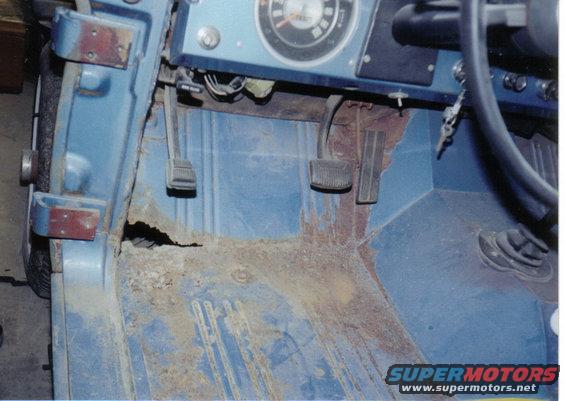 1974 Ford Bronco interior driver's side floorboard showing extensive rust and pedals