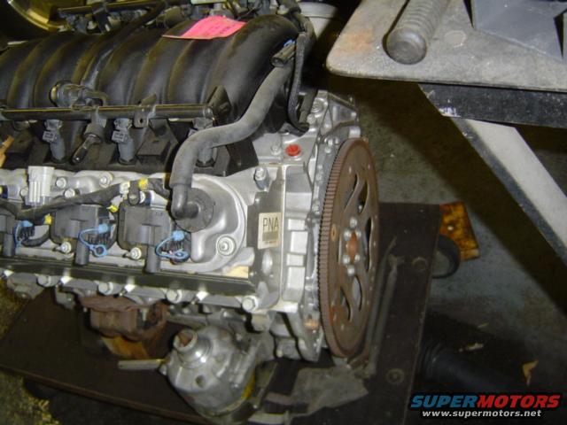 engine assembly on a stand, showing intake manifold, fuel injectors, and flywheel