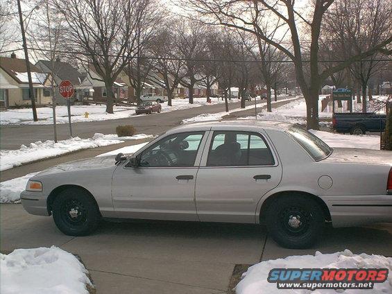 Silver sedan parked on a driveway in the snow, side view