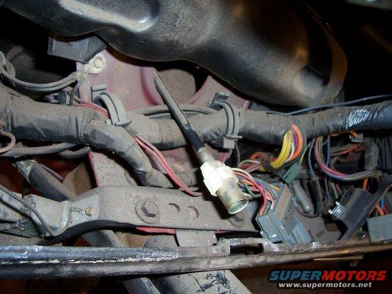 Close-up of a vehicle's interior wiring harness with a sensor and various cables