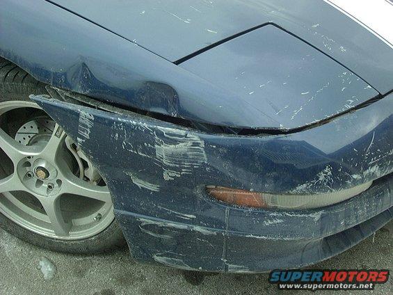 Damaged blue car front fender and bumper with white racing stripes on hood