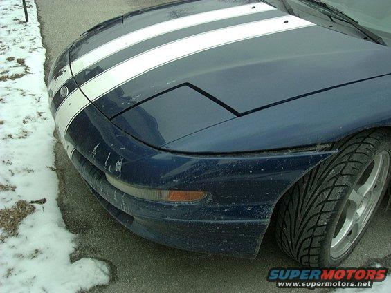Front view of a blue 1995 Ford Probe with white racing stripes and pop-up headlights