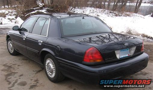 Dark blue sedan, 1998 Ford Crown Victoria, rear 3/4 view, with chrome wheels and a license plate
