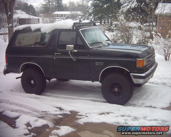 Black 1987 Ford Bronco in snow, side view