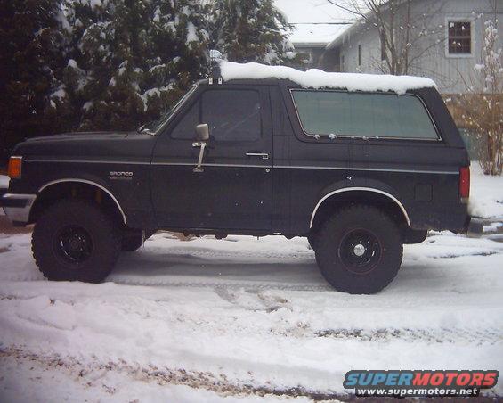 Black 1987 Ford Bronco parked in snow, side view