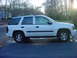 2005 Chevrolet TrailBlazer - A white 2005 Chevrolet TrailBlazer is seen from the side on a paved surface with trees in the background.