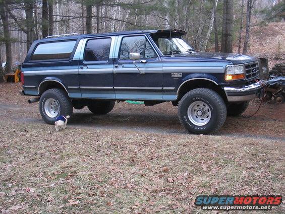 Blue Ford Bronco Centurion with aftermarket wheels and a sun visor parked outside