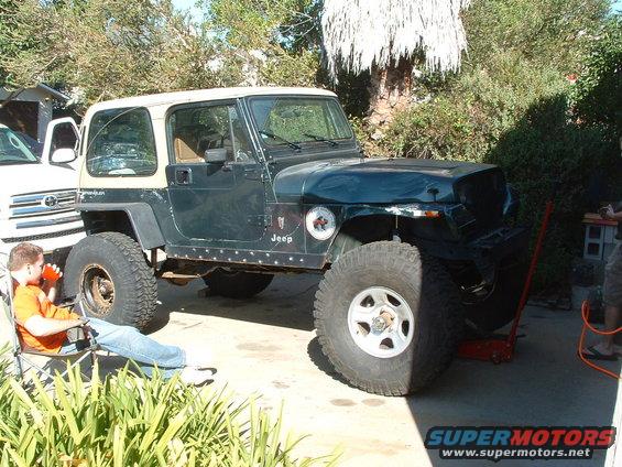 Dark green Jeep YJ with tan hardtop, lifted with large tires