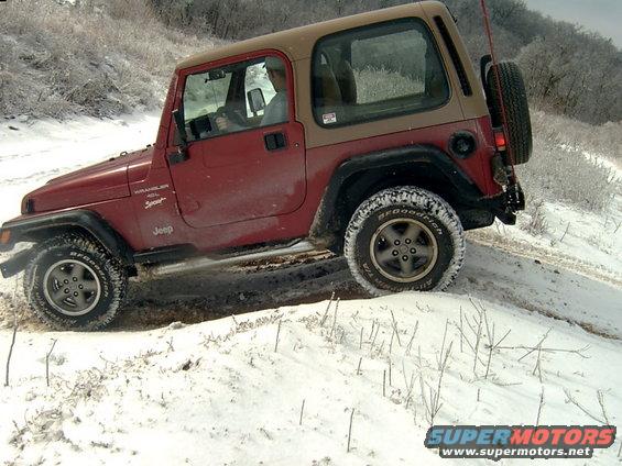 Red 1998 Jeep TJ driving on a snowy trail