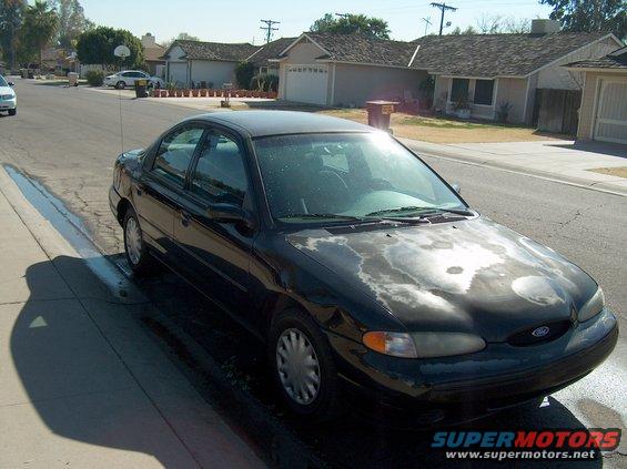 Black sedan with peeling hood paint parked on a residential street