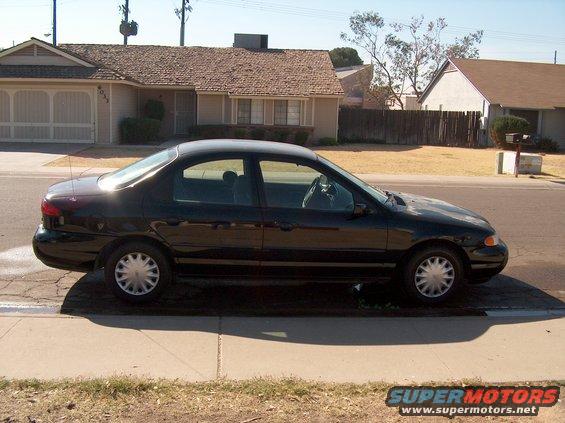 Black sedan parked on a residential street, side view