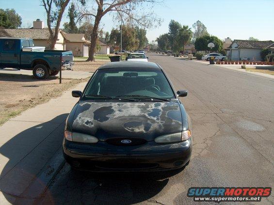 Black sedan with faded paint on hood, parked on street, front view