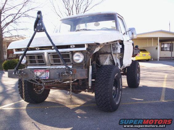 White Ford truck with custom bumper and tow hitch, front end is damaged