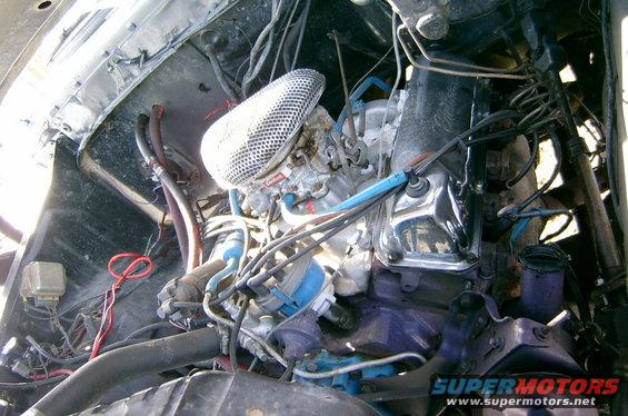 Engine bay with carburetor, air filter, and wiring. Some parts are painted purple