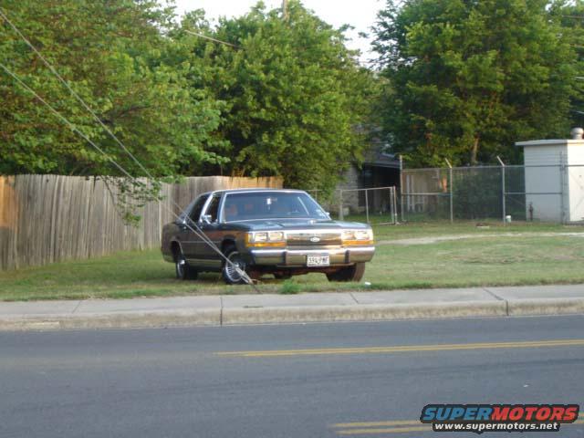 1988 Ford Crown Victoria LTD parked on grass next to a wooden fence. License plate is visible