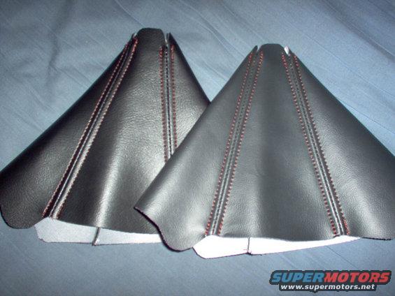 Two black leather shift boot covers with red stitching on a blue fabric background