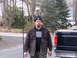2006 Ford F1 - A man wearing a plaid shirt and beanie stands in front of a black pickup truck, with another white vehicle visible in the background.